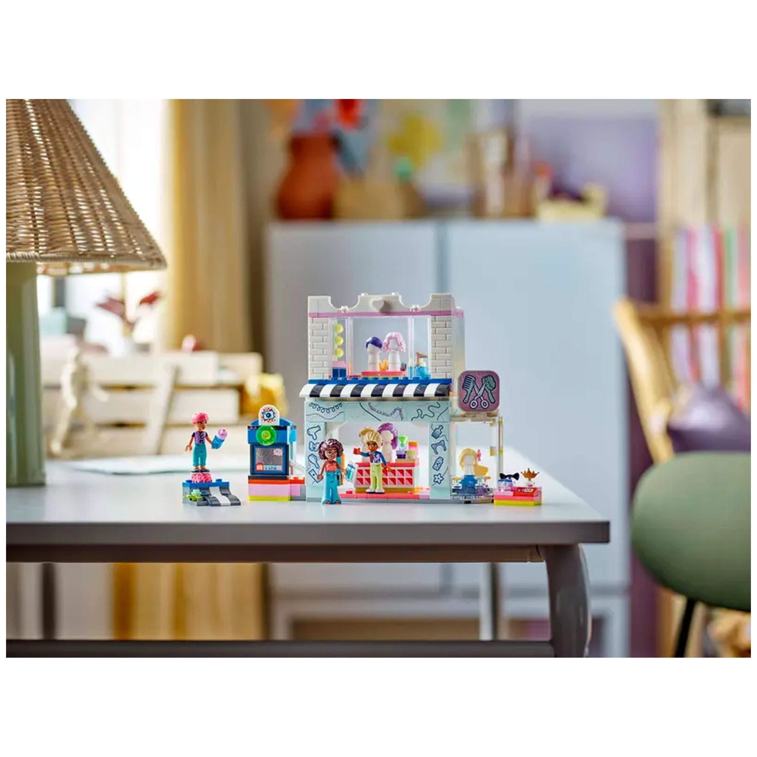 A colorful LEGO Friends Hair Salon and Accessories Store set displayed on a table, featuring three mini-dolls, beauty accessories, and a vibrant two-story structure.