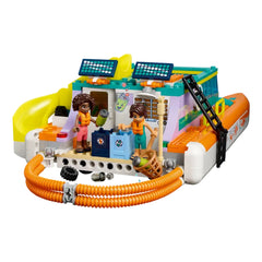 Two LEGO® Friends figures stand on a colorful Sea Rescue Boat, which features solar panels and interactive elements. The boat is equipped with nets and tools for ocean cleanup, promoting marine conservation. Bright colors include yellow, orange, and teal, creating an engaging adventure scene.