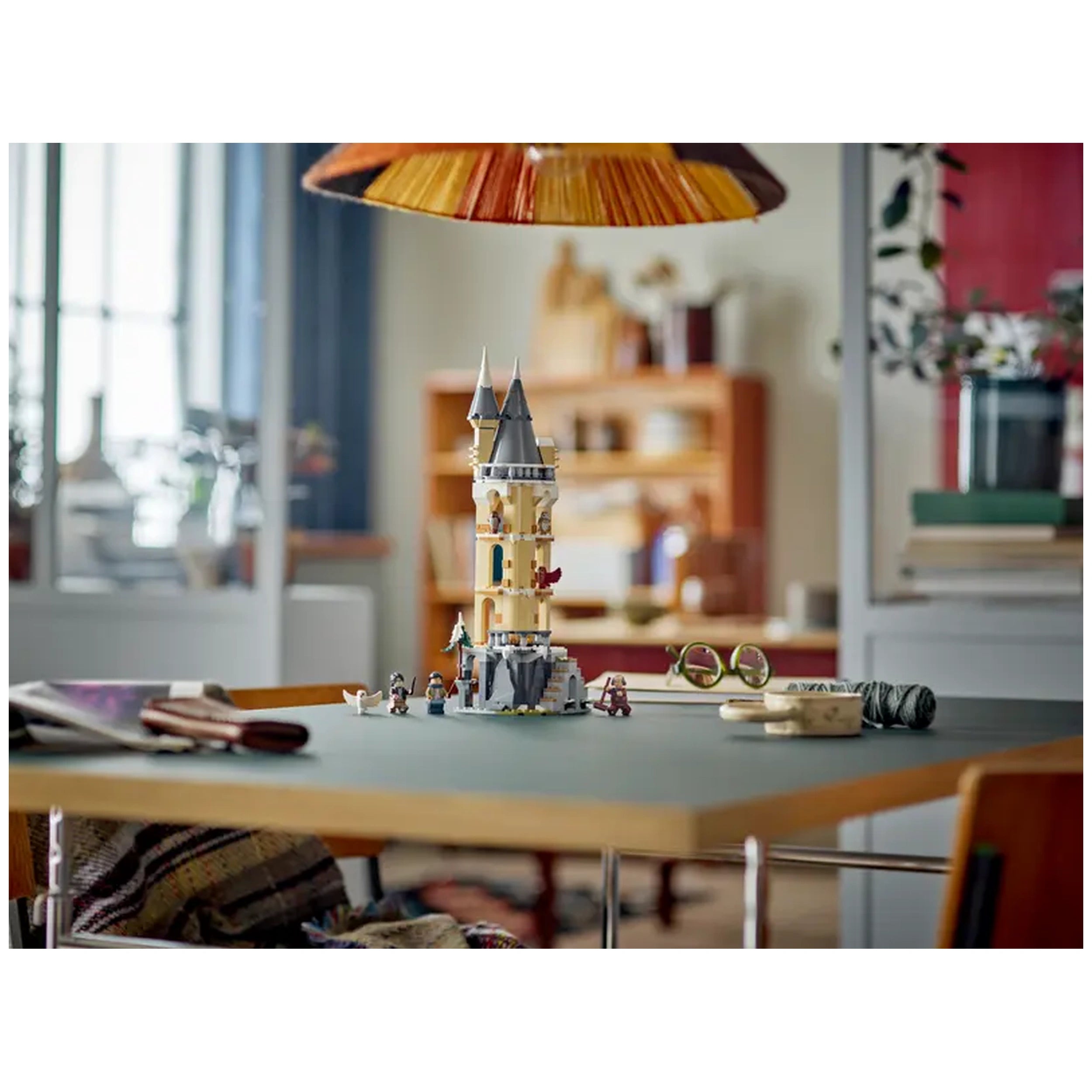 LEGO Harry Potter Hogwarts Castle Owlery construction set on a green table, surrounded by playful figures and colorful accessories.