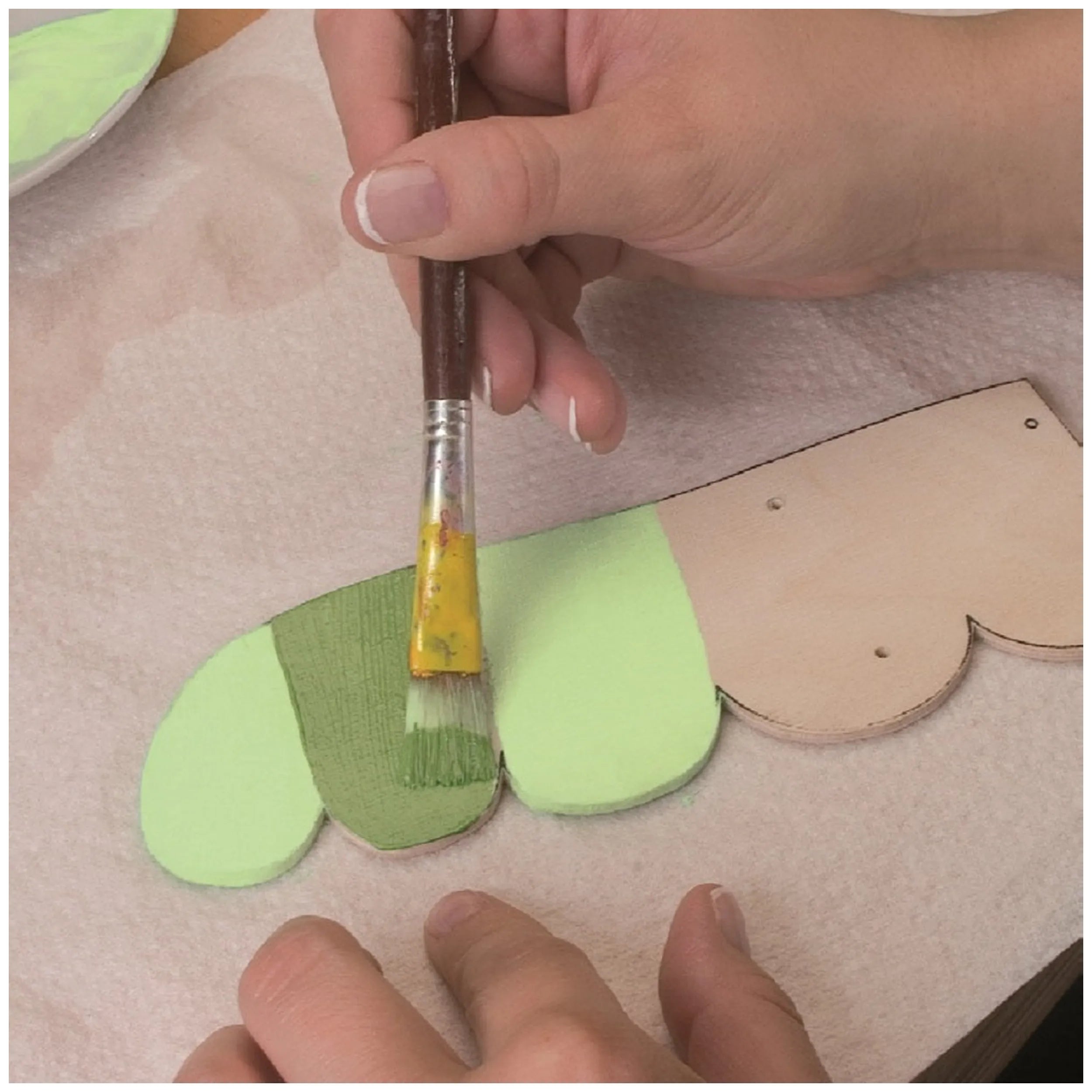 Hand painting wooden fretwork with light green paint using a brush from the Prebaro Fretwork Kit.