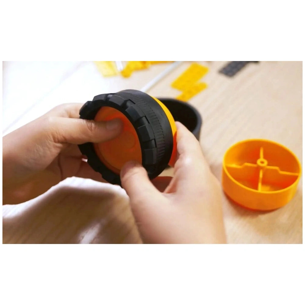 Child assembling an orange and black wheel from the Alexander Pro Muck Truck Constructor set.