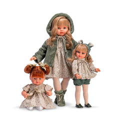 Three dolls in floral dresses with bows, featuring red and blonde hair. The central doll wears a green hooded coat.