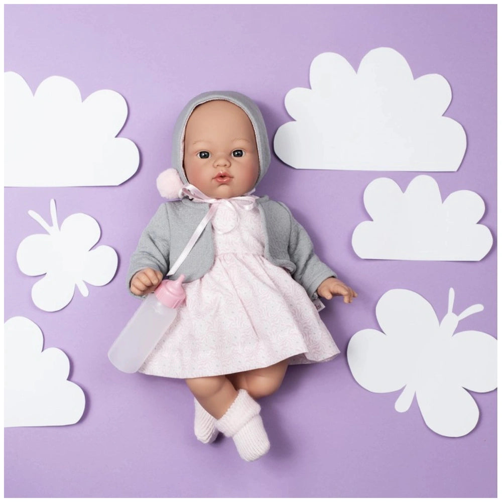 Koke doll in pink dress and gray jacket, lying on lavender background with white clouds and butterflies.