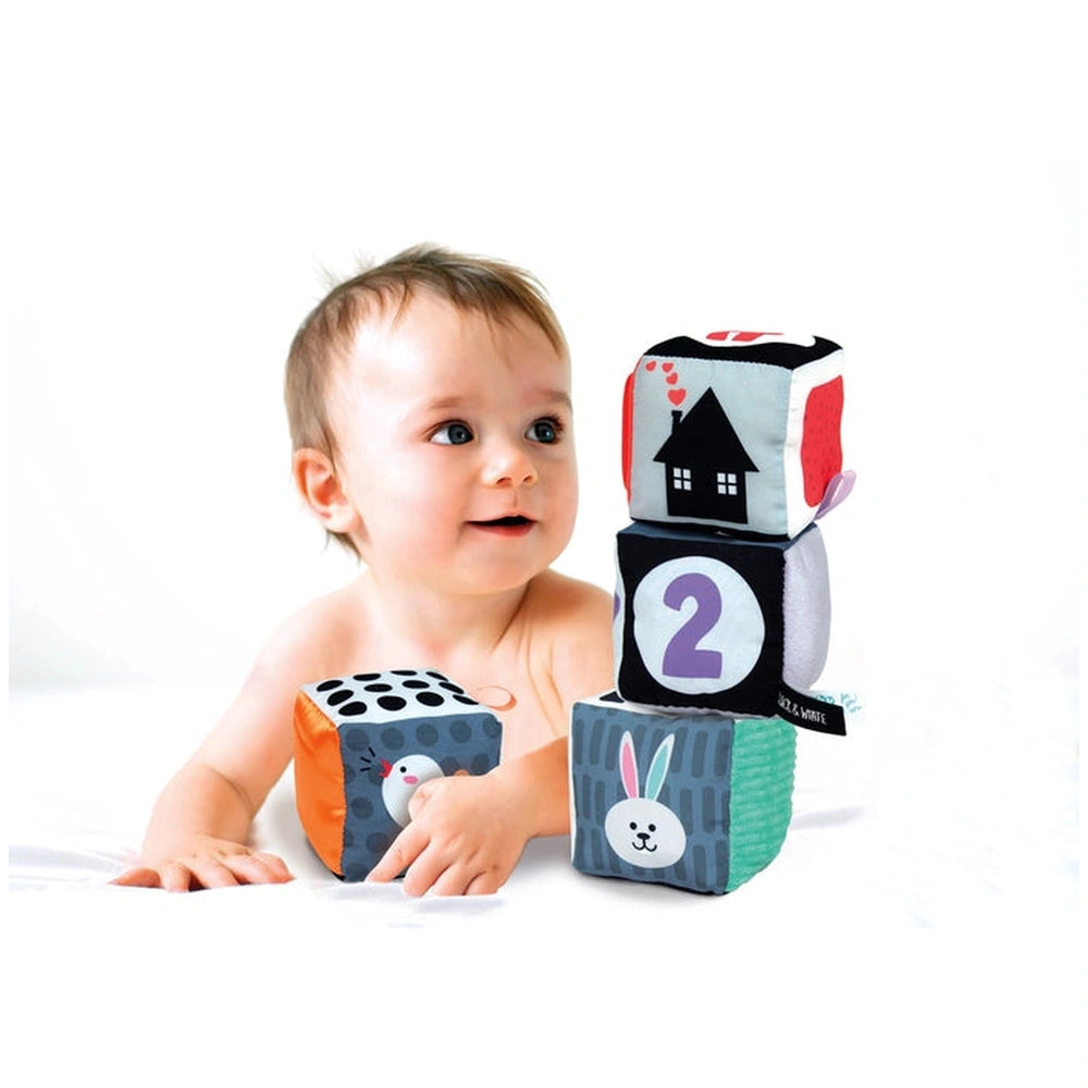 Black & White Soft Activity Blocks for babies, with a light-colored mat and a curious baby looking at the camera.