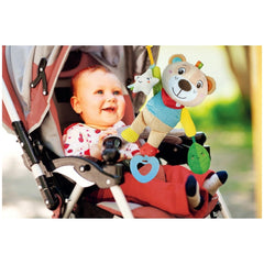 Baby Clementoni Easy-Peasy Soft Bear stuffed animal with blue scarf, held by a smiling baby in a stroller with a pink canopy.