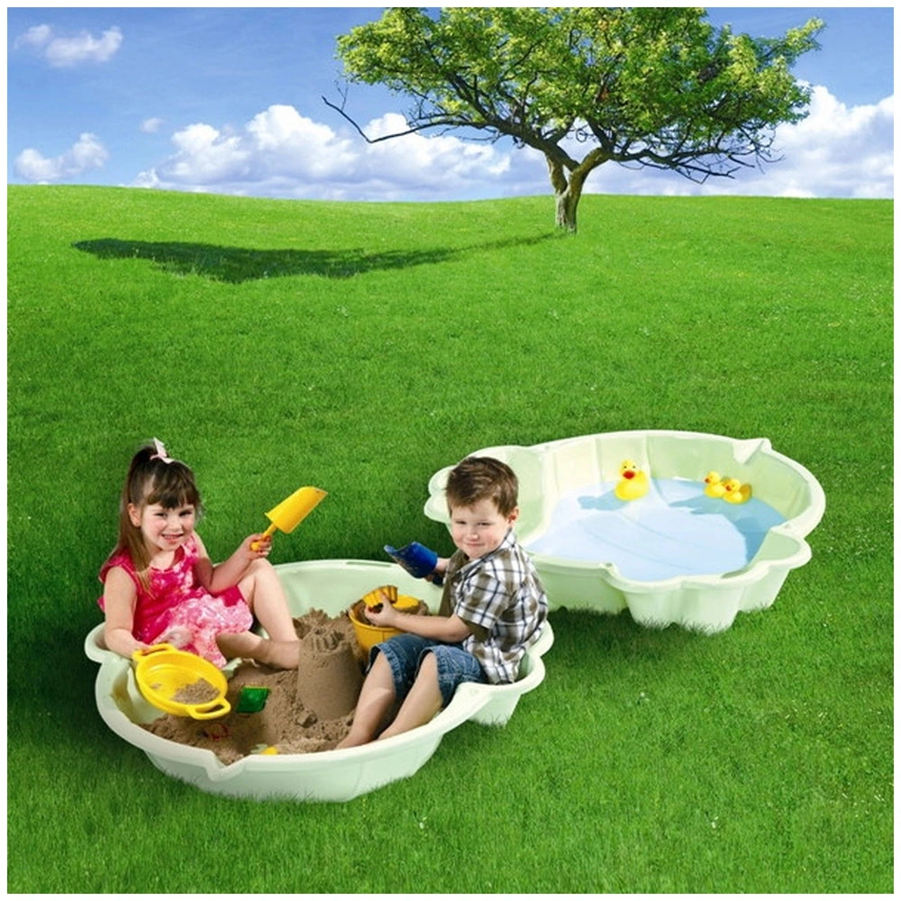 Beach Bee double crab sandbox with two children playing, surrounded by green grass, a tree, and a blue sky with clouds.