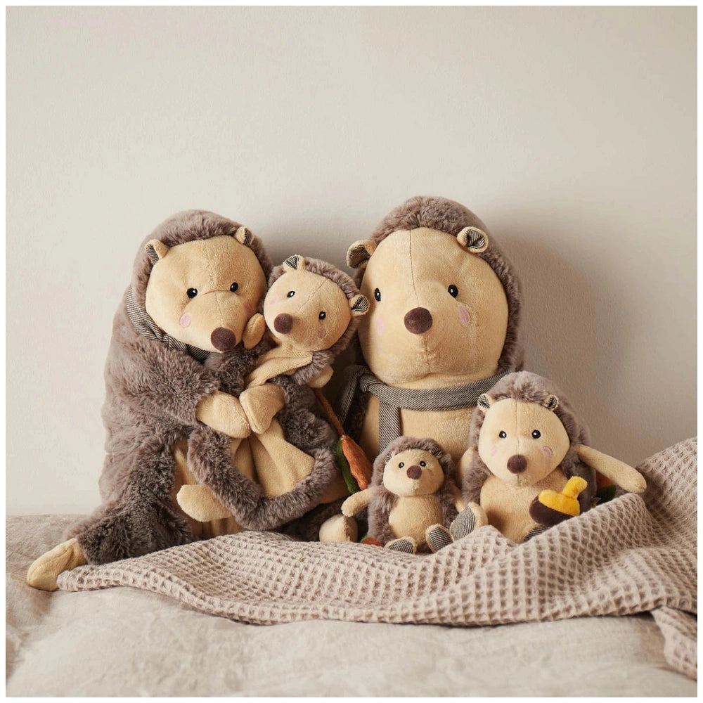 A cozy arrangement of four adorable hedgehog stuffed animals, featuring soft chocolate and oatmeal colors, snuggled together on a textured blanket.
