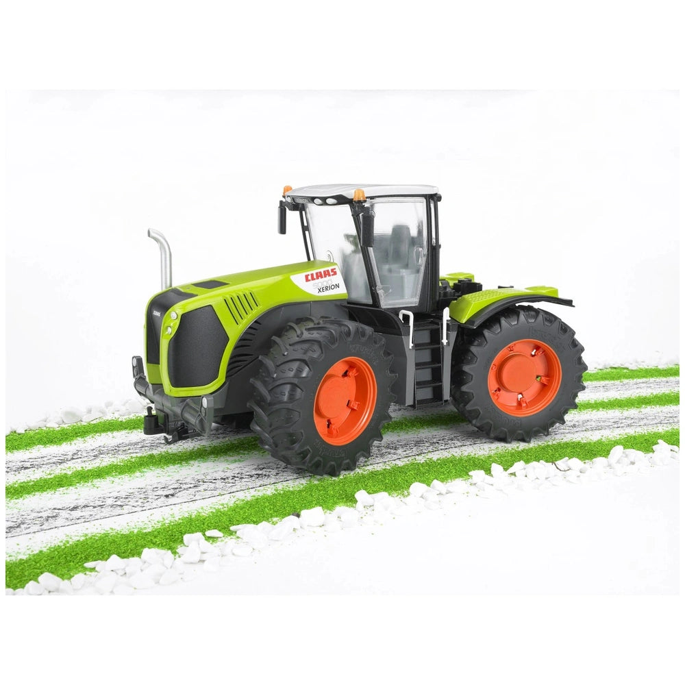 Claas Xerion 5000 toy tractor with green body and orange wheels on a striped green and white track.