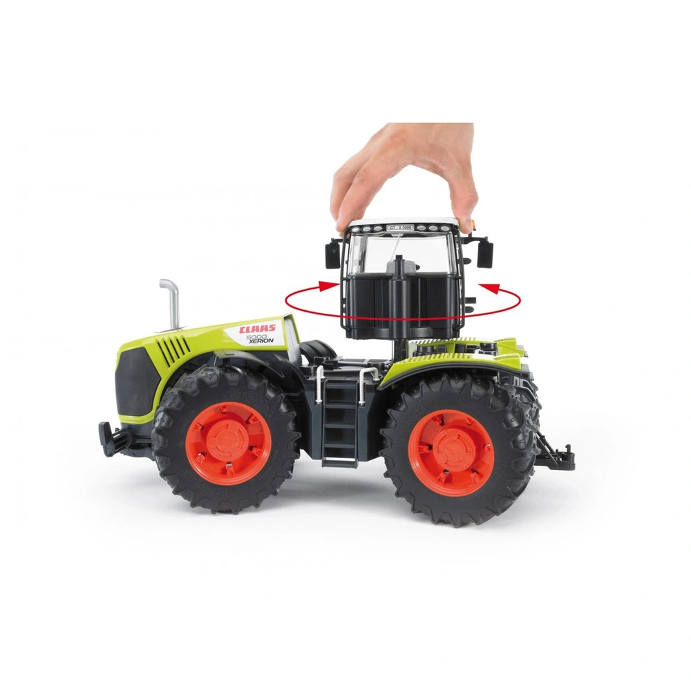 Hand rotating cab of Bruder Claas Xerion 5000 toy tractor, featuring large tires and vivid green and orange design.
