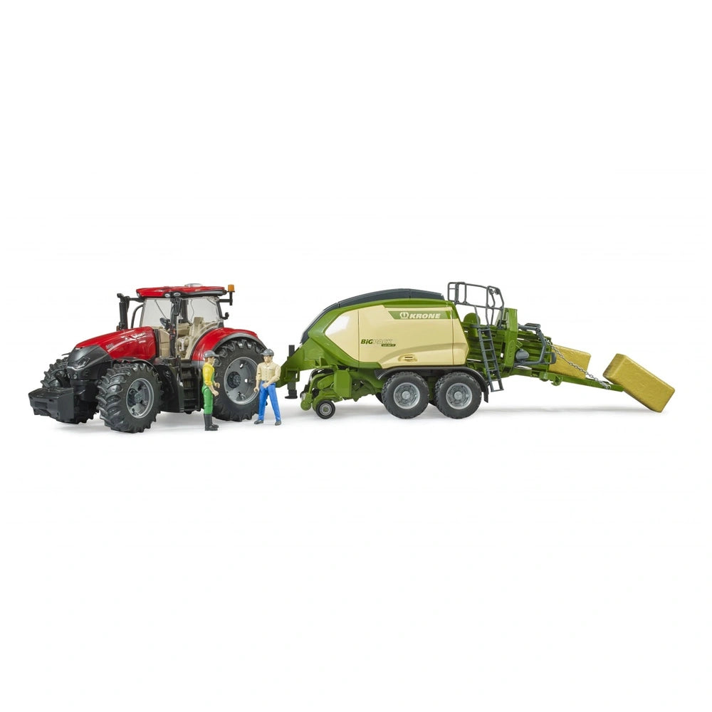 Red tractor towing green Krone Big Pack baler toy, with two hay bales and three figures beside it.