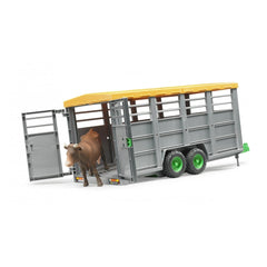 Toy livestock trailer with yellow roof and green wheels, featuring a brown cow exiting through open gates.