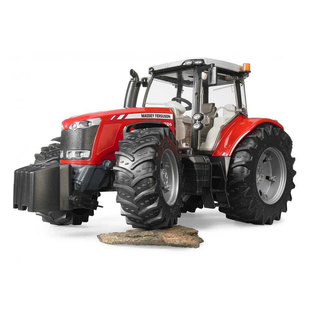 Red Bruder Massey Ferguson 7624 toy tractor with large tread tires and a glass cabin, placed on a rock surface.