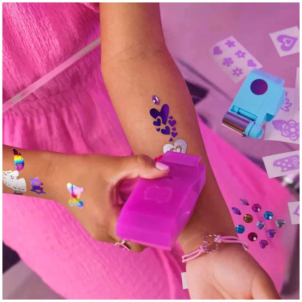Cool Maker Shimmer Me Body Art Set showcases colorful decorations on a person's arm and hand, enhancing their pink outfit.
