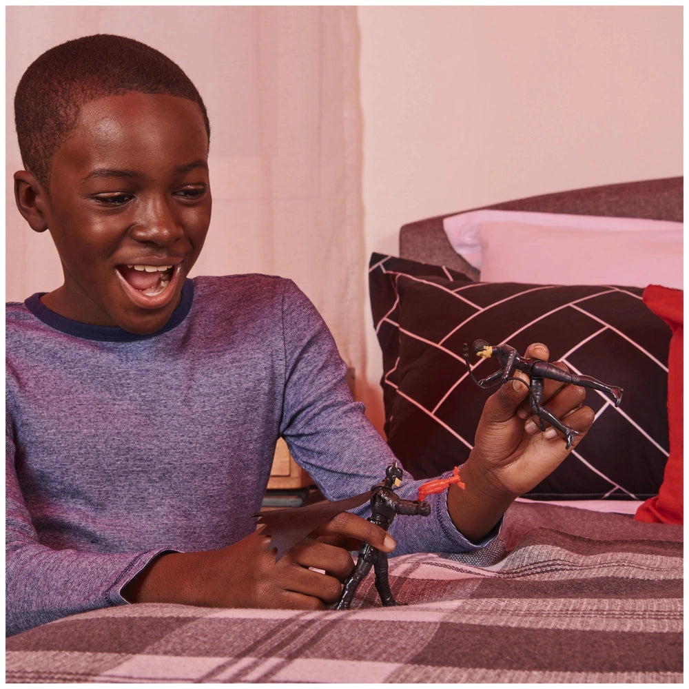 Batman Selina Kyle action figure held by a smiling boy indoors, with a plaid bedspread and a black and white pillow in the ba