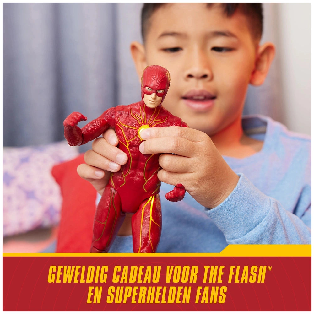 A young boy examines a red The Flash action figure with yellow highlights, showcasing excitement in a cozy indoor setting.