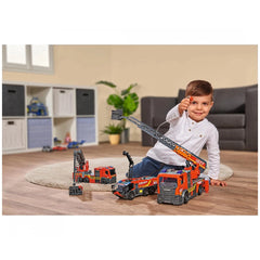 Dickie City Fire Ladder Truck play vehicle in front of a boy on a light rug, with a gray couch and green plant in the backgro