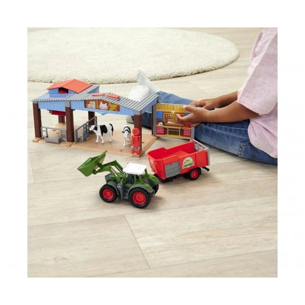 Dickie Farm Station playset with a blue and orange toy barn, red truck, and a child holding toys on a wooden floor.