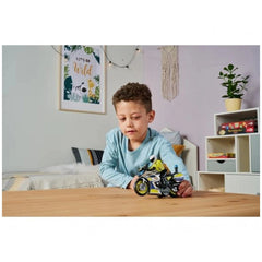 Dickie police motorbike toy with sounds and lights, played with by a young boy on a wooden table surrounded by colorful decor