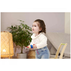 Eichhorn Baby Wooden Rattle Rabbit held by a young child in a cozy indoor setting with plants and a woven basket nearby.