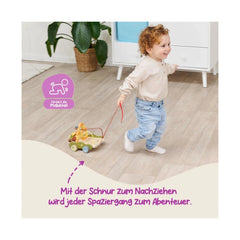 EICHHORN Bee Happy Pullalong Wagon being held by a smiling child in a light-colored wooden room with a potted plant.