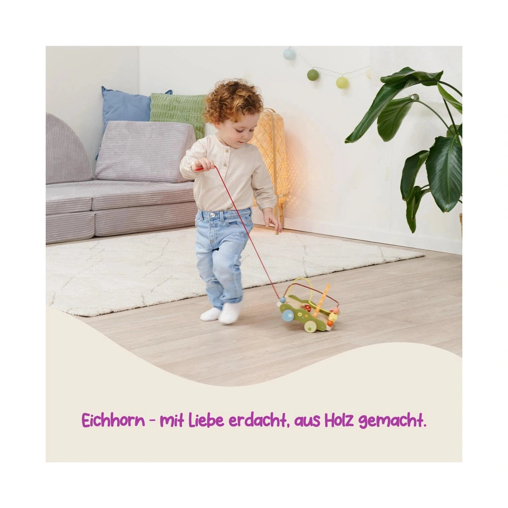 EICHHORN Bee Happy Pullalong Wagon is being pulled by a young child on a wooden floor, surrounded by a cozy indoor setting.