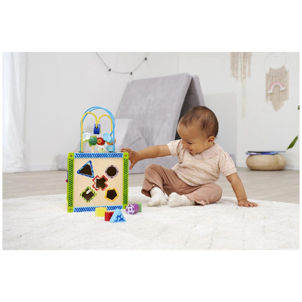 Eichhorn Color Little Play Center toy is being explored by a young child sitting on a white carpet, focused and engaged.