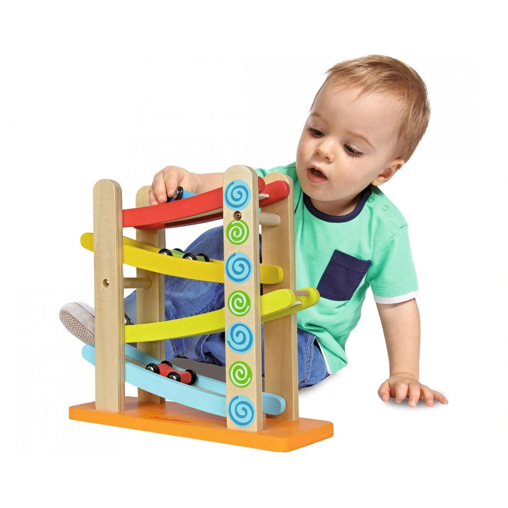 Eichhorn Color Motor-Racing Circuit toy engages a toddler with colorful wooden components and a red handle on the floor.