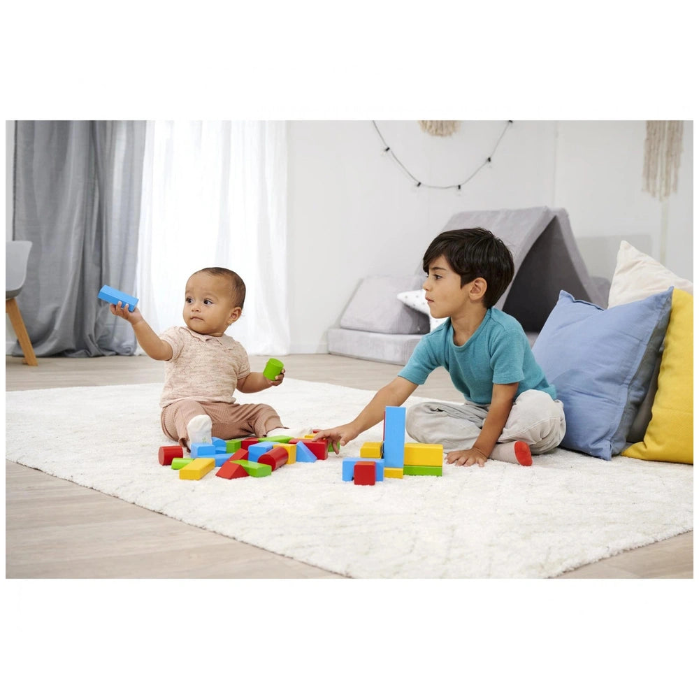 Eichhorn coloured wooden blocks are being played with by two children on a white shag rug, surrounded by a bright living room