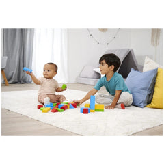 Eichhorn coloured wooden blocks are being played with by two children on a white shag rug, surrounded by a bright living room