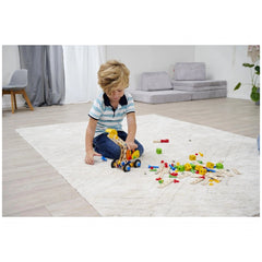 Eichhorn Constructor 3in1 construction set toys are scattered around a child in a blue striped shirt playing on a white rug.