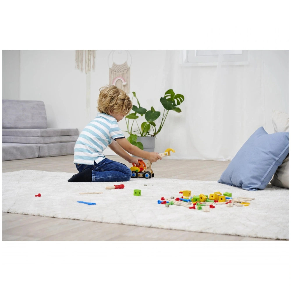 Eichhorn Constructor 3in1 construction set toys are scattered on a white rug as a child plays intently in a cozy living room.