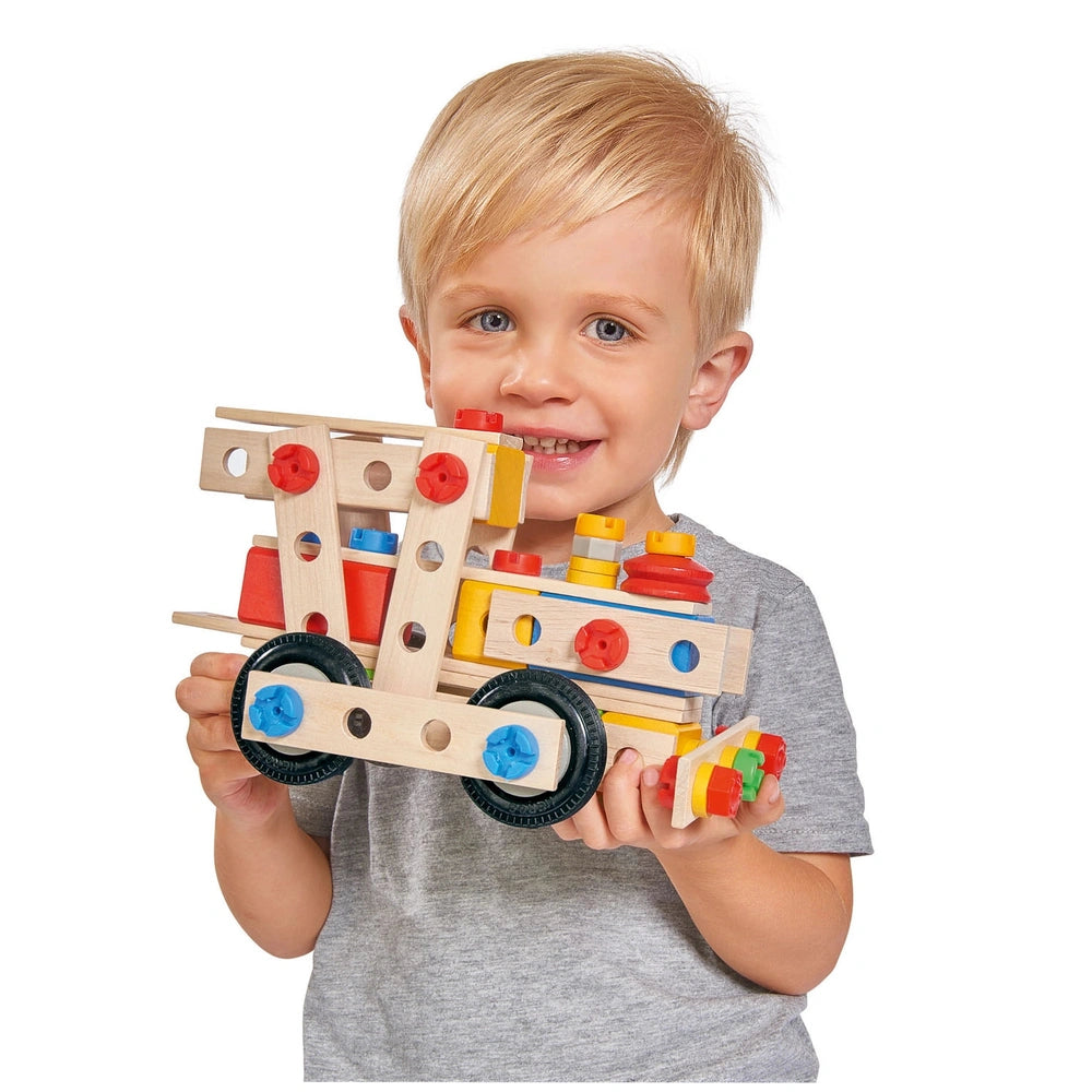 Eichhorn Constructor 4 in 1 construction set held by a smiling child, featuring colorful wooden wheels and gears.