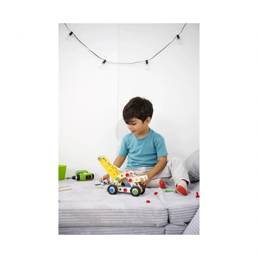 Eichhorn Constructor 4in1 construction set with a young boy playing with a colorful plastic toy car on gray fabric.