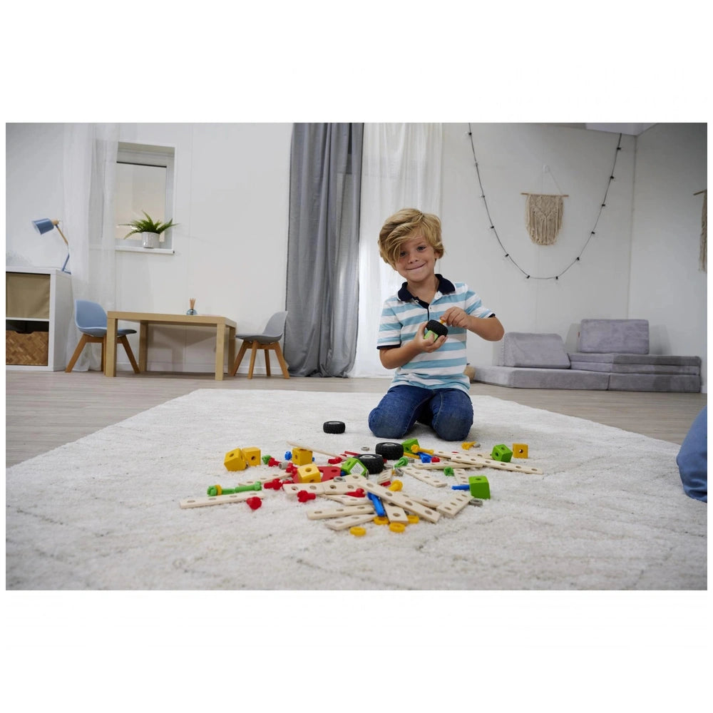Eichhorn construction set toys are being enjoyed by a smiling boy sitting on a white carpet in a modern, well-lit room.