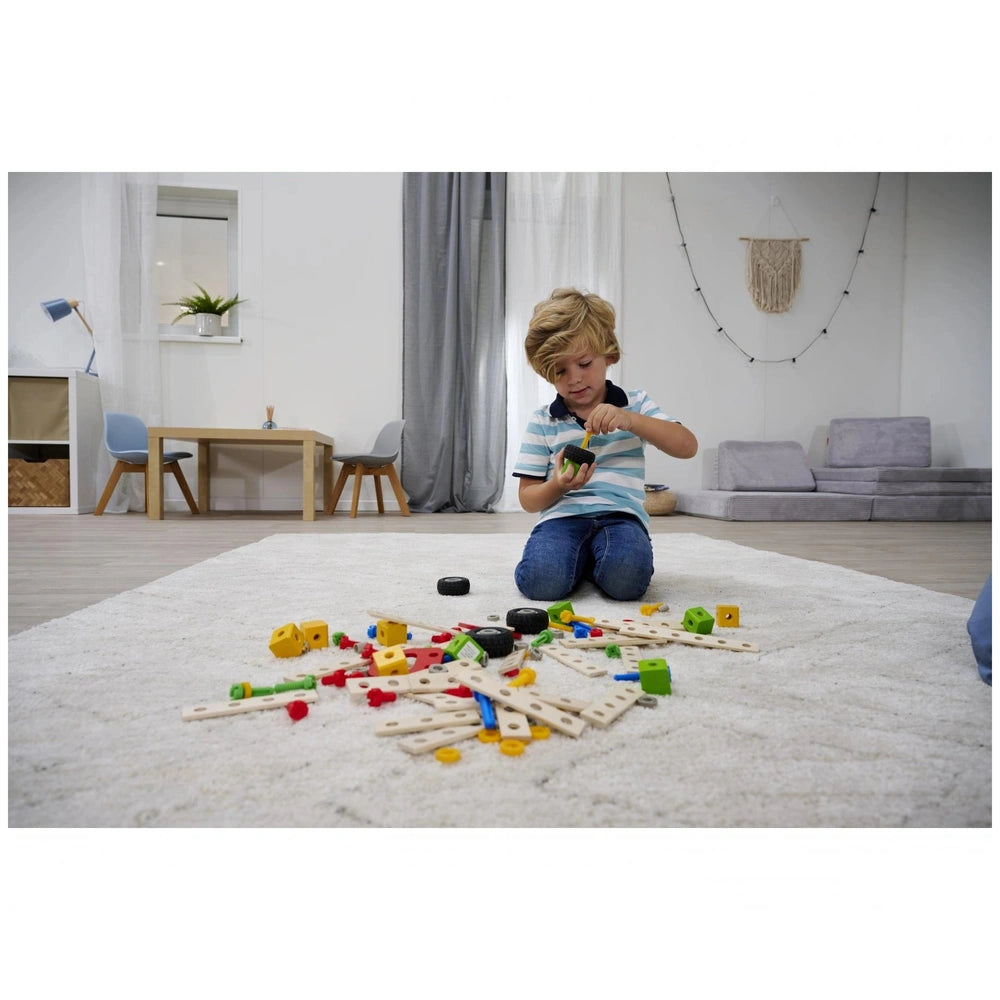 Eichhorn Constructor Accessories set features a child engaged with colorful wooden and plastic toys in a modern, minimalist r
