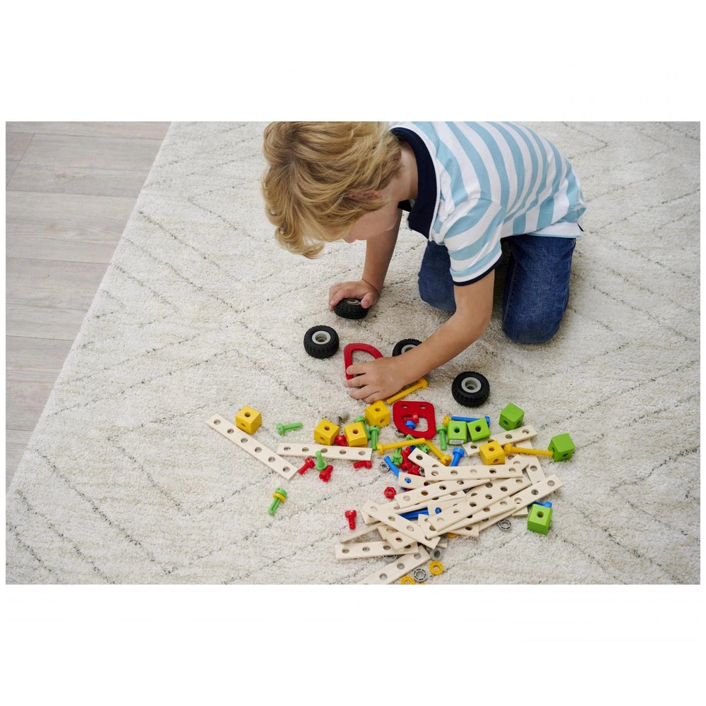 Eichhorn Constructor Accessories set with a boy playing on a carpet, surrounded by colorful wooden blocks and a red toy.