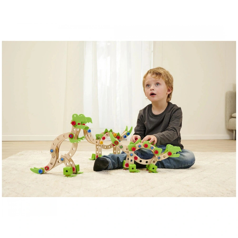 Eichhorn Constructor Dinosaur construction set with bright wooden pieces is being actively manipulated by a young child on a 