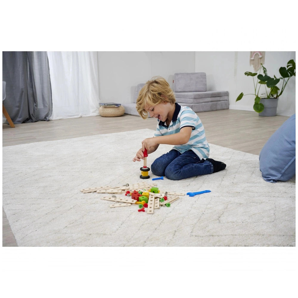 Eichhorn Constructor Expansion Set with 75 pieces, features a child playing on a white carpet in a cozy living room.