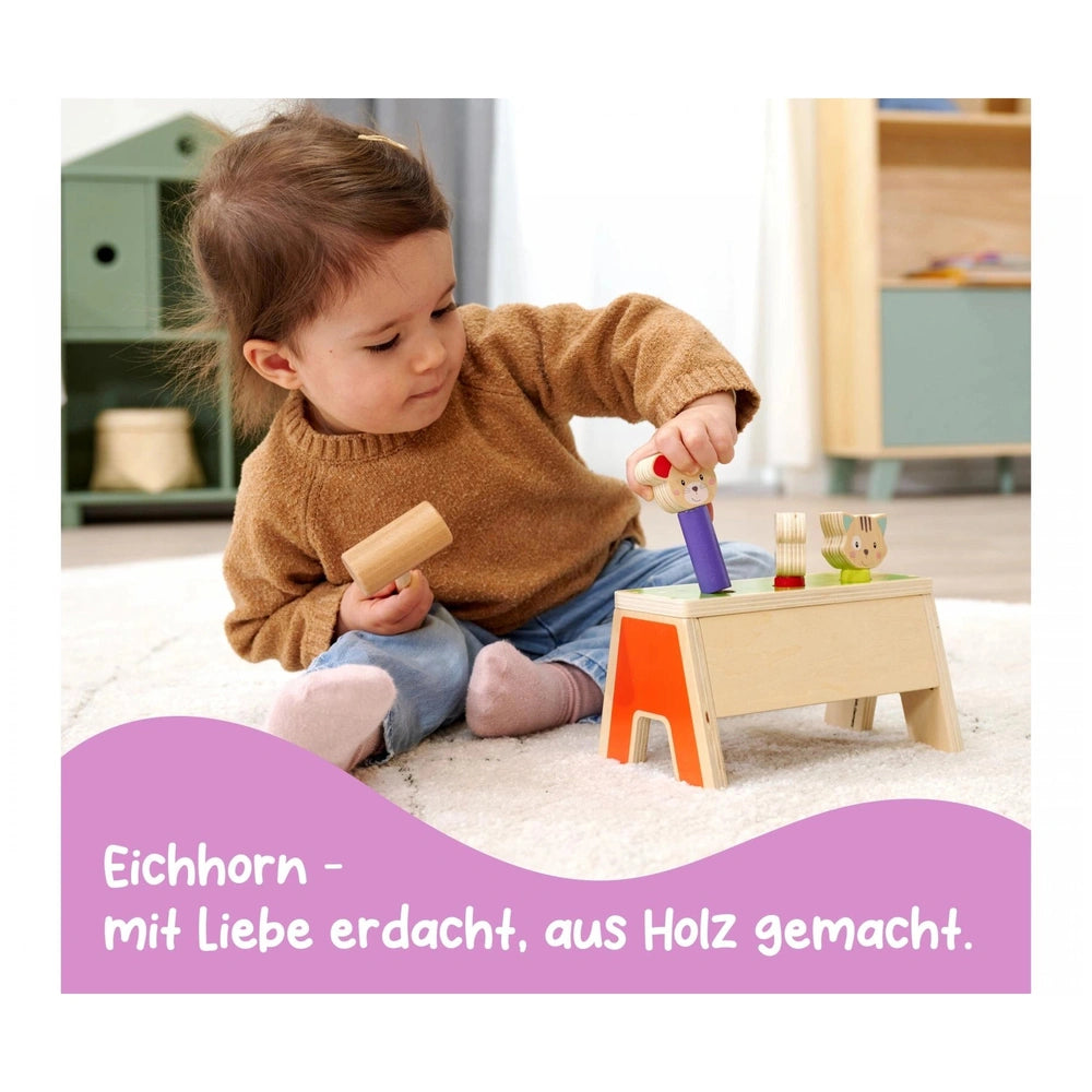 Eichhorn Knocking Game Pop Up features a child playing with a wooden block and hammer in a cozy indoor playroom setting.