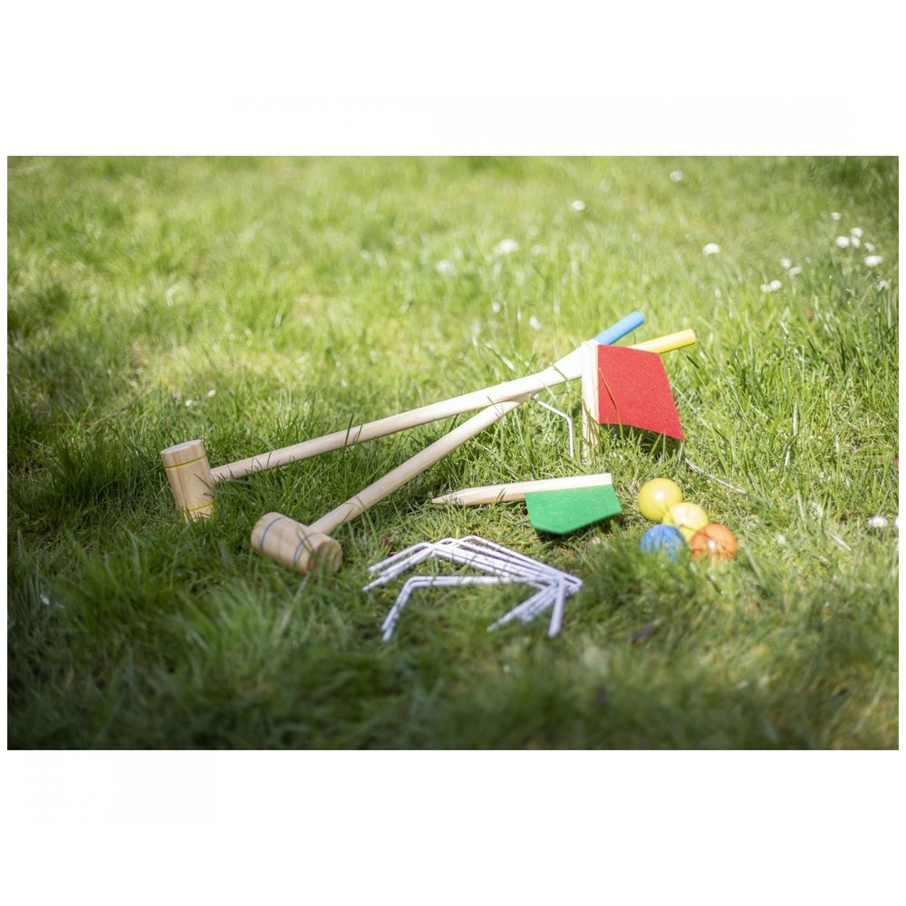 Eichhorn Outdoor Croquet Set components displayed on grass, featuring mallets, balls, and accessories in bright sunlight.