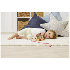 Eichhorn Pull Back Hedgehog toy in a childs hands, on a cozy shag rug with a light, airy background.