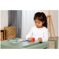 Eichhorn Wooden Domino Ralley: A young girl plays with colorful blocks at a green table, focused on her activity in a cozy in