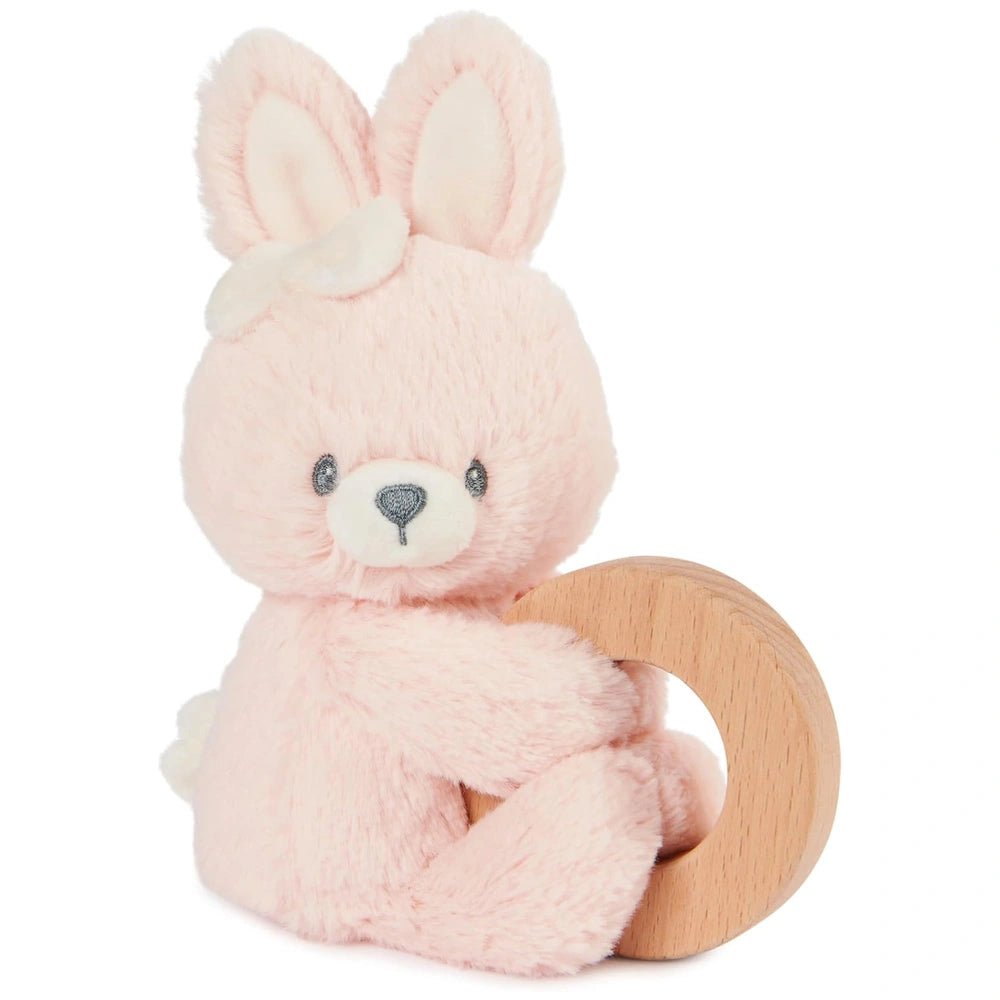 Soft pink plush bunny ring rattle with a white face and ears, sitting upright on a round wooden base.