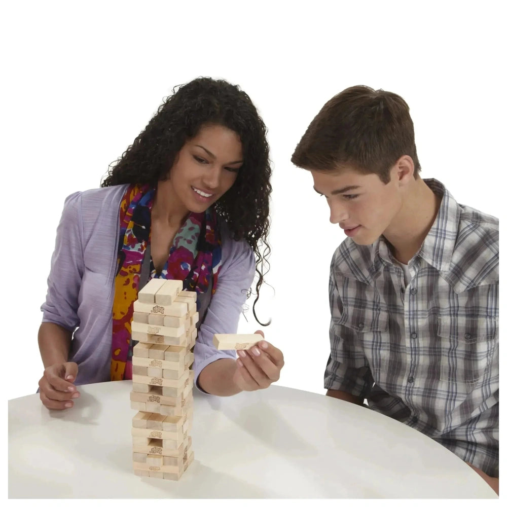 HASBRO Jenga Family Game with two players, a woman in a colorful scarf and a man in a plaid shirt, on a white table.