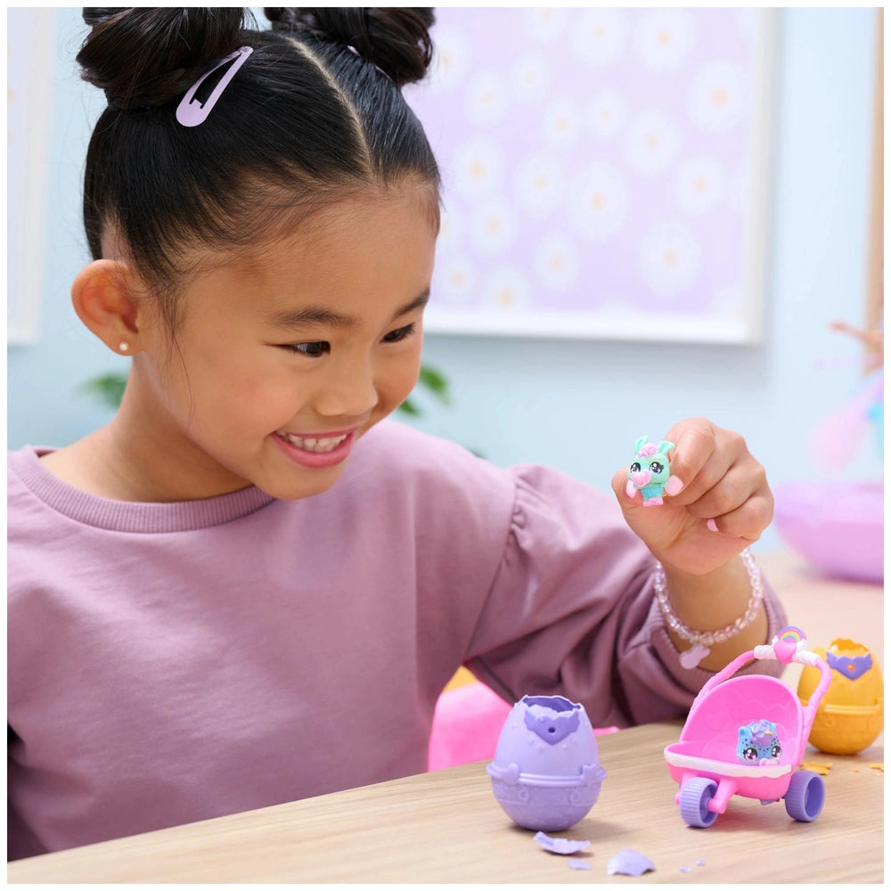 Hatchimals Alive Hatch N’ Stroll Playset features a young girl joyfully engaging with colorful toy eggs and a pink toy car.