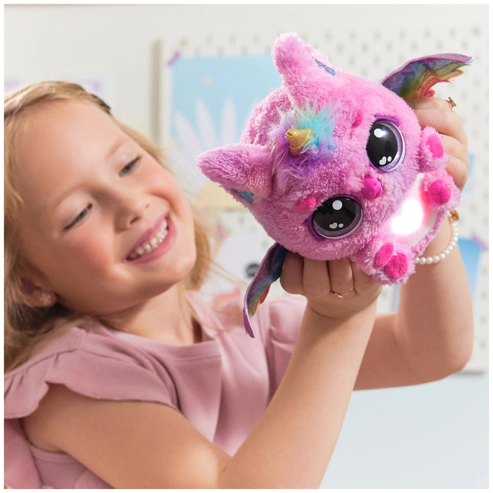 Hatchimals Alive Mystery Hatch Pufficorn plush toy in pink, held by a smiling girl indoors, showcasing its vibrant colors and