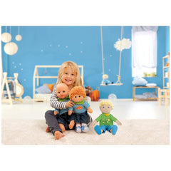 Heless dolls playset features a young girl in a striped shirt playing with three colorful dolls on a white carpet against a b
