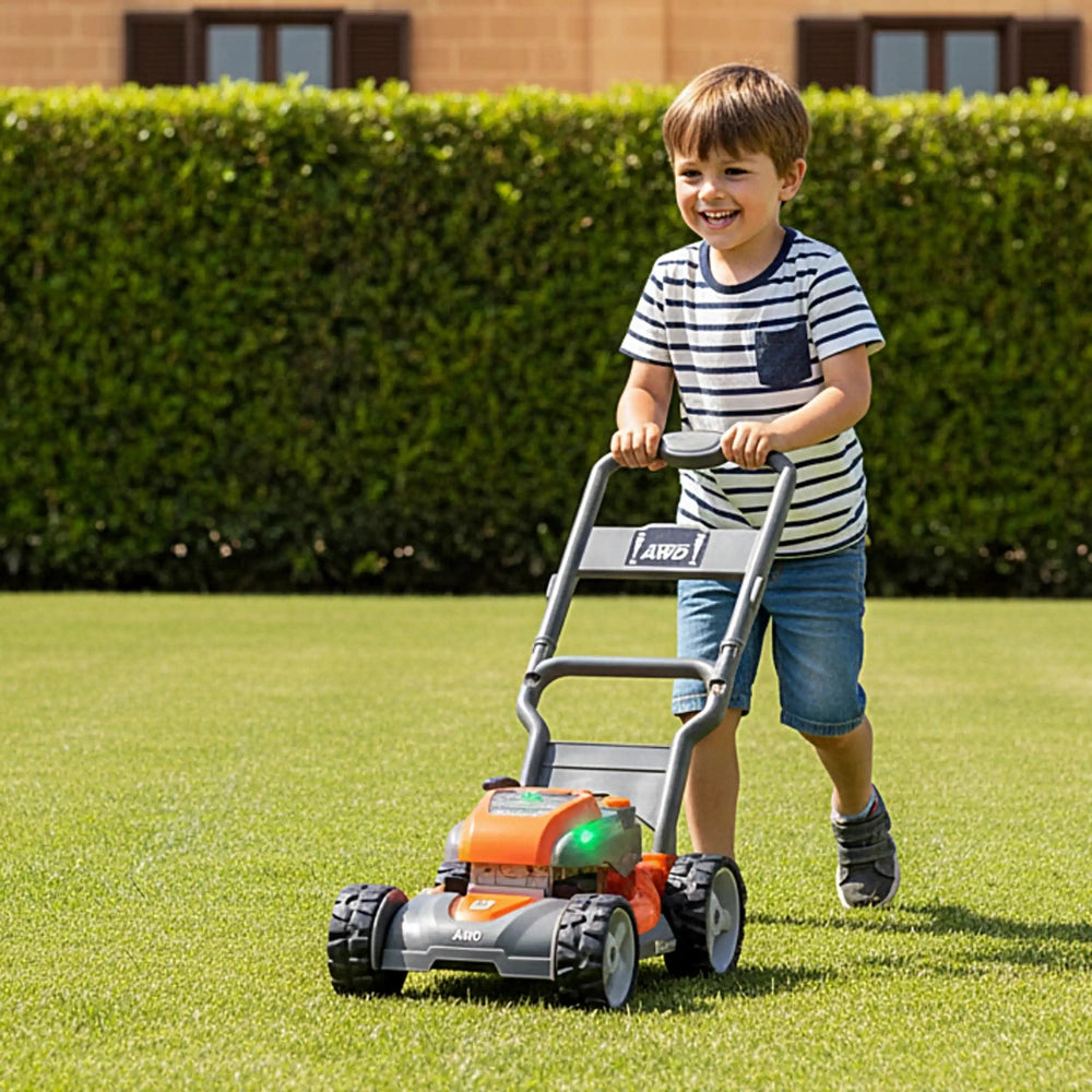 Boy in striped shirt and blue shorts plays with orange and gray Husqvarna toy lawn mower in green yard by brown building.