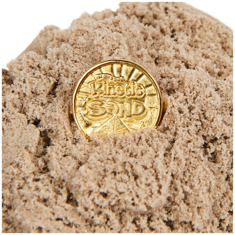 Kinetic Sand Mummy Tomb features a golden coin partially buried in textured sand, showcasing its shiny metallic surface and i