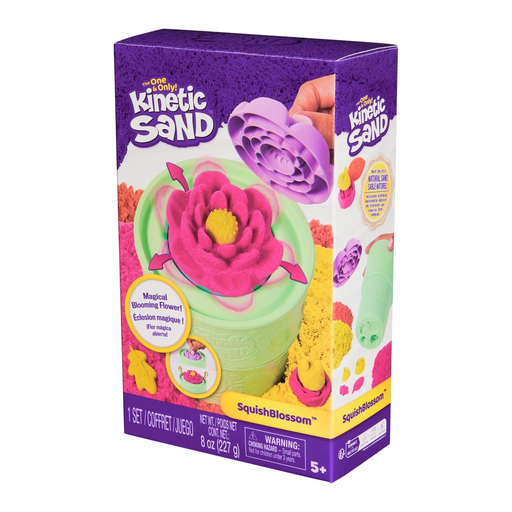 Kinetic Sand Squish Blossom toy packaging features a vibrant pink and purple sand mold, green squeeze bottle, and clear windo